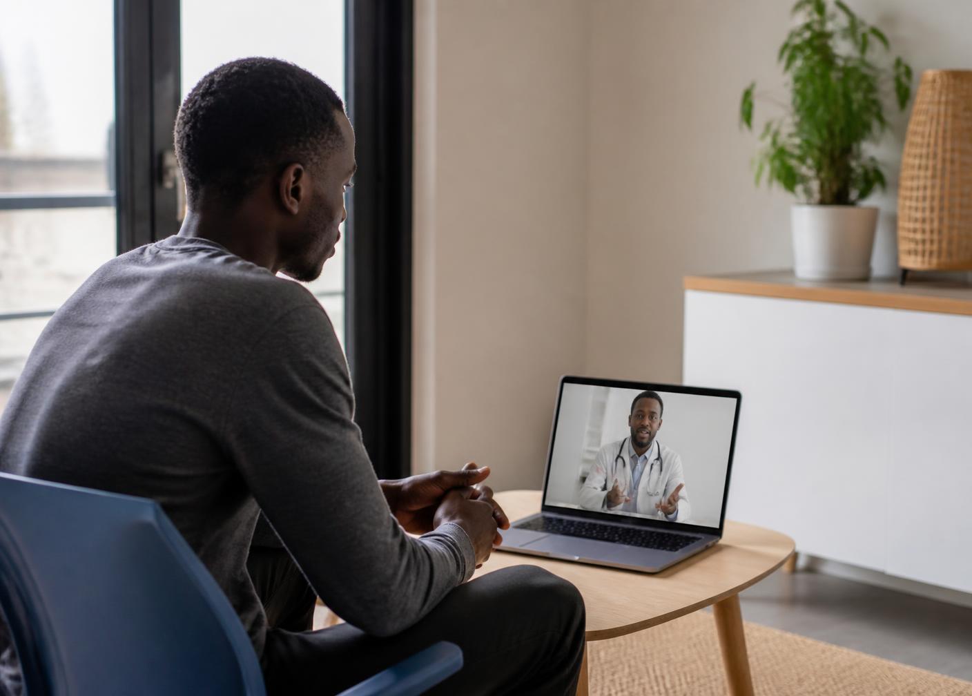 Jeune homme en téléconsultation avec un praticien depuis son domicile